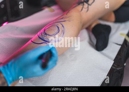 ein tattoo-Meister, der mit der Freihand-Technik, moderne Kunst, auf einem Bein malt. Hochwertiges Foto Stockfoto