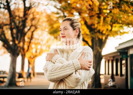 Herbstporträt einer jungen, glücklichen Frau mit weißem Strickpullover Stockfoto