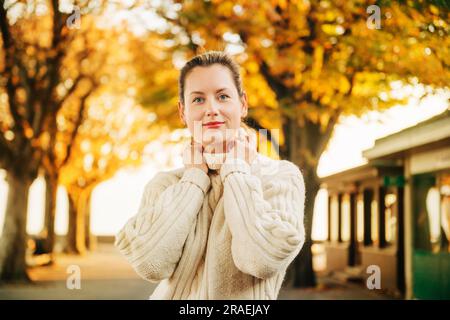 Herbstporträt einer jungen, glücklichen Frau mit weißem Strickpullover Stockfoto