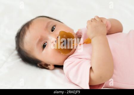 Baby-Mädchen saugen mit Schnuller auf dem Bett Stockfoto