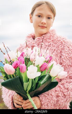 Junges Mädchen, das draußen posiert, mit frischen Tulpenblüten Stockfoto