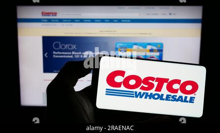 Person, die ein Smartphone mit dem Logo der US-amerikanischen Firma Costco Wholesale Corporation auf dem Bildschirm vor der Website hält. Konzentrieren Sie sich auf das Display des Telefons. Stockfoto