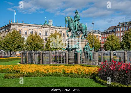 Kopenhagen, Dänemark - 15. September 2010: Geen Bronze King Christian V Statue Gruppe auf Kongens Nytorv umgeben von Blumen unter blauem Himmel. Historisches C Stockfoto