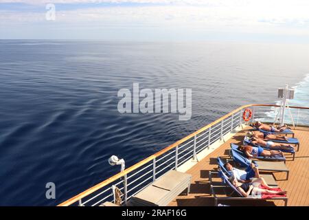 Kreuzfahrtgäste an Bord des P&O Kreuzfahrtschiffs Arcadia genießen die mediterrane Sonne und bräunen sich auf dem Weg nach Alicante, Spanien, am 2023. April. Stockfoto