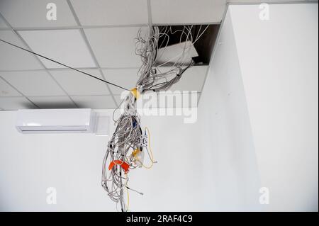 Elektrokabel hängen von der Decke. Kabel hängen von der Zimmerdecke. Im Bau befindliches Gebäude. In Arbeit. Stockfoto