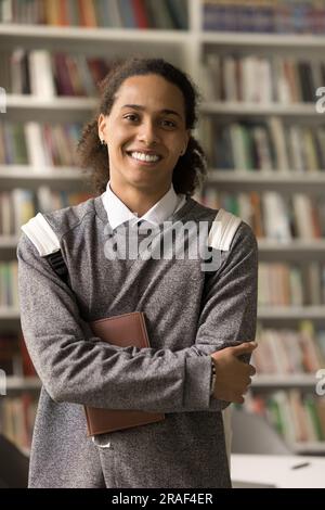 Ein selbstbewusster Schwarzer mit Rucksack, der in der Bibliothek posiert Stockfoto