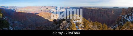 Aufnahme auf den Grand Canyon vom Südrand im Winter mit Schnee bei klarem Himmel mit Wolkenschleiern fotografiert von oben abends bei tief stehend Stockfoto