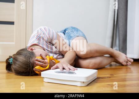 Schuppen und eine depressive Frau, die auf dem Boden liegt und ihr Gesicht mit den Händen bedeckt. Stockfoto