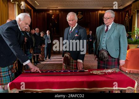 König Karl III. Mit Designer Mark Dennis (links), Lord Lyon (rechts) und dem neuen Elizabeth Sword im Palace of Holyroodhouse in Edinburgh. Das Schwert, benannt nach Königin Elizabeth II., wird Teil der Ehren von Schottland sein, zu denen die Krone und das Zepter gehören. Es wird dem König während des Nationaldienstes von Thanksgiving und der Einweihung in der St. Giles-Kathedrale am Mittwoch, den 5. Juli, überreicht. Foto: Montag, 3. Juli 2023. Stockfoto