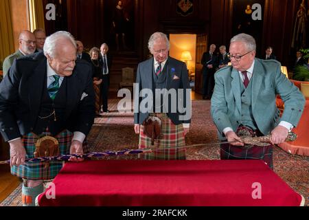 König Karl III. Mit Designer Mark Dennis (links), Lord Lyon (rechts) und dem neuen Elizabeth Sword im Palace of Holyroodhouse in Edinburgh. Das Schwert, benannt nach Königin Elizabeth II., wird Teil der Ehren von Schottland sein, zu denen die Krone und das Zepter gehören. Es wird dem König während des Nationaldienstes von Thanksgiving und der Einweihung in der St. Giles-Kathedrale am Mittwoch, den 5. Juli, überreicht. Foto: Montag, 3. Juli 2023. Stockfoto