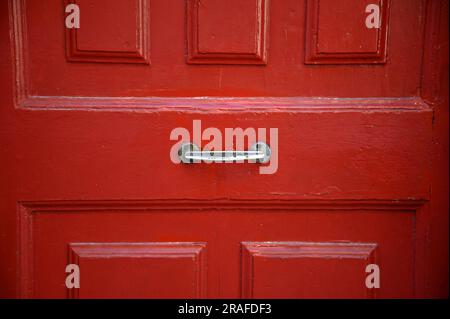 Hellrote Holztür mit einem antiken Zinngriff in Monreale Sizilien, Italien. Stockfoto