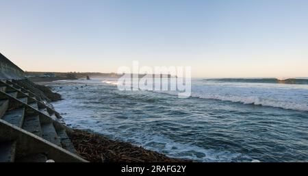 "Küste bei Cullen, Schottland, mit Wellen, die gegen die Hafenmauer krachen. Stockfoto