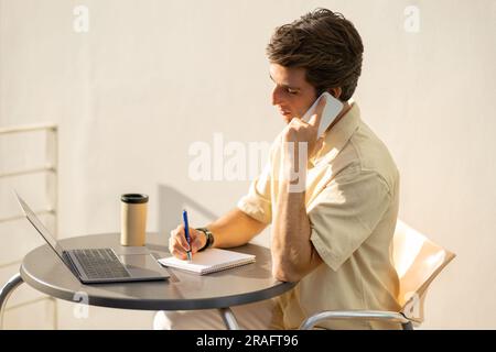 Junger Unternehmer, der im Café arbeitet, hat einen Anruf Stockfoto