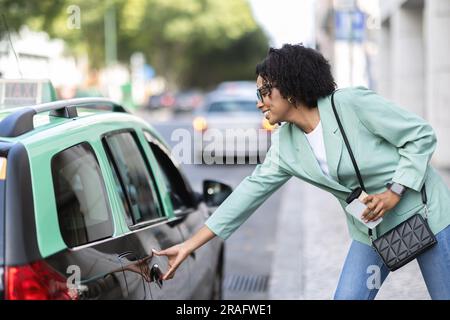 Wunderschöne afroamerikanische junge Dame, die Taxi nimmt Stockfoto