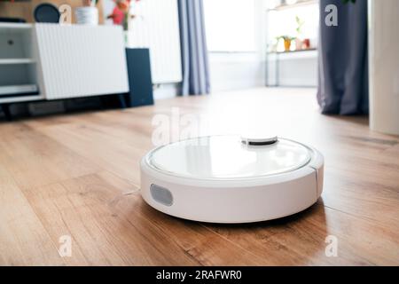 Weißer Roboter-Staubsauger auf dem Boden im Wohnzimmer, Smart-Home-Gerät Stockfoto