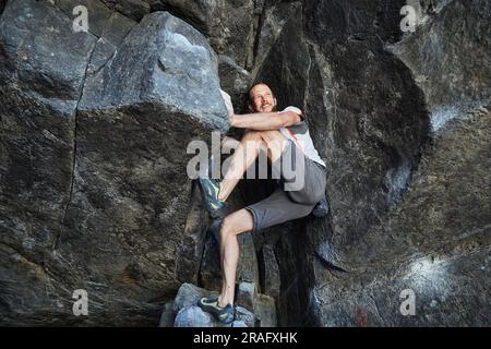 Männlicher Kletterer auf Felsbrocken Stockfoto