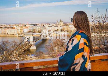 Mädchen mit Sonnenbrille in einer farbenfrohen Jacke mit Budapest im Hintergrund Stockfoto