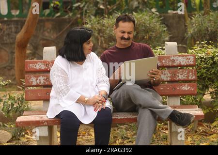Wunderschönes Old Indian Happy Pair sitzt zusammen im Park und hat fröhliche Momente im Leben. Gemeinsame Urlaubsplanung. Stockfoto