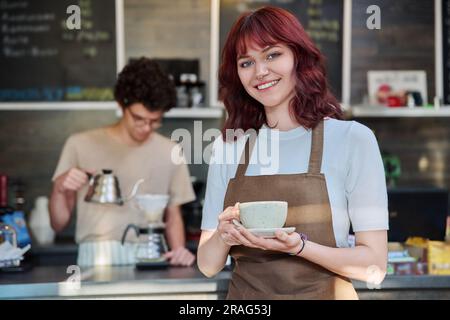 Porträt einer jungen weiblichen Kellnerin vor der Theke im Café Stockfoto