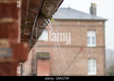 Eine Dachrinne in einem Gebäude, eine alte Abflussrohrnaht, Wasser fließt durch verfaultes Metall, es gibt einen Platz für eine Inschrift. Hochwertiges Foto Stockfoto