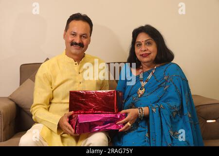 Ein glücklicher Indianer bringt seiner Frau in Saree ein wunderbares Geschenk. Beide tragen indische ethnische Kleidung auf Diwali und feiern das Festival. Stockfoto