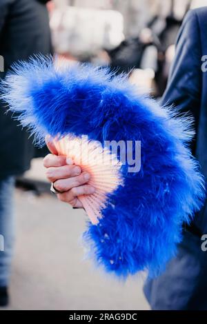 Der Mann hält einen handgefertigten blauen Federventilator in der Hand Stockfoto