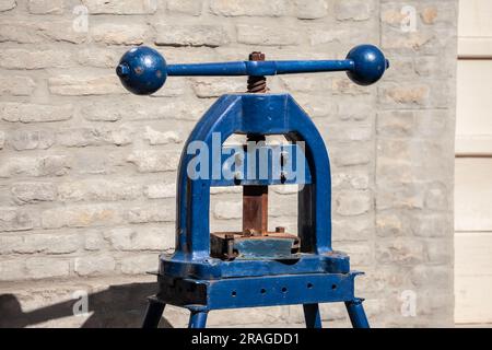 Bild einer Handdruckpresse auf einer Ziegelwand. Eine Druckerpresse ist eine mechanische Vorrichtung, mit der Druck auf ein gefärbtes Oberflächenwiderstand ausgeübt wird Stockfoto