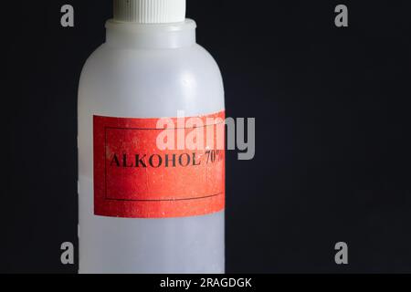 Bild einer 70%-Alkohol-Plastikflasche isoliert auf schwarzem Hintergrund. Eine solche Flasche Alkohol wird zur Desinfektion im Gesundheitswesen verwendet. Stockfoto