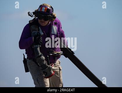 Chief Aviation Boatswain's Mate (Fuel) Jason Campbell aus Phoenix, der dem größten Flugzeugträger USS Gerald R. FordÕs (CVN 78) in der Luftabteilung von worldÕs zugeteilt wurde, transportiert am 2. Juli 2023 einen Tankschlauch auf dem Cockpit. Gerald R. Ford ist die USA Der neueste und fortschrittlichste Flugzeugträger, NavyÕs einen Generationssprung in den USA darstellt NavyÕs Fähigkeit, Energie auf globaler Ebene zu projizieren. Die Gerald R. Ford Carrier Strike Group befindet sich in einem geplanten Einsatz in den USA Marinestreitkräfte Europa Einsatzgebiet, angestellt von den USA Sechste Flotte, die die Interessen der USA, Verbündeten und Partner verteidigt. (USA Stockfoto