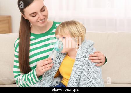 Mutter hilft ihrem kranken Sohn bei der Inhalation von Verneblern zu Hause Stockfoto