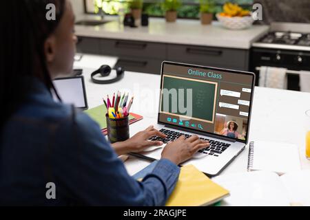 Vielfältige Schülerin mit Lehrerin, die während eines Laptop-Videogesprächs Unterricht hat Stockfoto