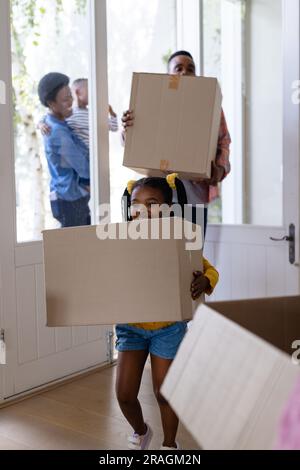 afroamerikanischer Vater und afroamerikanische Tochter, die Pappkartons bei sich tragen, während sie in ein neues Zuhause eintreten Stockfoto