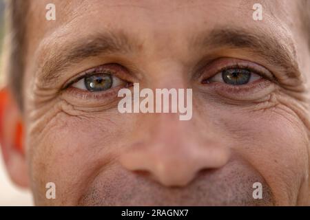 Porträt Nahaufnahme eines glücklichen weißen männlichen Tennisspielers, der draußen lächelt Stockfoto