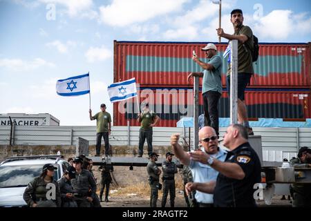 Haifa, Israel. 03. Juli 2023. Israelische Demonstranten schwenken die israelische Flagge neben Polizeibeamten und Grenzpolizisten während einer Demonstration gegen die Justizreform, die das Hafentor von Haifa blockiert. Obwohl Israel über eine große Militäroperation in der Stadt Dschenin im Westjordanland lachte, gelobten Demonstranten gegen die Bemühungen der Regierung, das Justizsystem zu reformieren, den Zugang zum Hafen von Haifa zu blockieren, da auch im Ausland Dutzende Kundgebungen stattfanden. Kredit: SOPA Images Limited/Alamy Live News Stockfoto