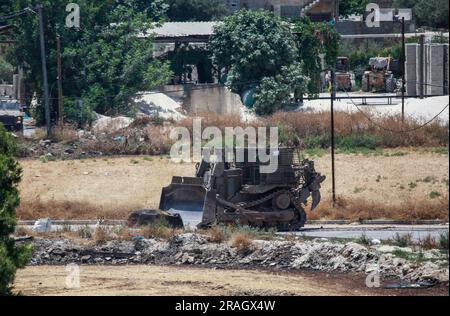 Dschenin, Palästina. 03. Juli 2023. Ein israelischer militärischer Bulldozer trifft im Flüchtlingslager Dschenin während eines Überfalls auf das Lager in der Nähe der Stadt Dschenin, nördlich des besetzten Westjordanlands, ein. Ein Angriff der israelischen Armee auf Dschenin, der mit mehreren Luftangriffen begann, gefolgt von einem Bodenangriff auf mehr als 100 gepanzerte Fahrzeuge. 9 Palästinenser wurden bei diesem Angriff getötet und Dutzende schwer verletzt. Kredit: SOPA Images Limited/Alamy Live News Stockfoto