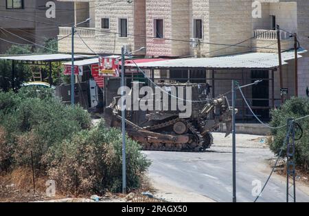 Dschenin, Palästina. 03. Juli 2023. Ein israelischer militärischer Bulldozer trifft im Flüchtlingslager Dschenin während eines Überfalls auf das Lager in der Nähe der Stadt Dschenin, nördlich des besetzten Westjordanlands, ein. Ein Angriff der israelischen Armee auf Dschenin, der mit mehreren Luftangriffen begann, gefolgt von einem Bodenangriff auf mehr als 100 gepanzerte Fahrzeuge. 9 Palästinenser wurden bei diesem Angriff getötet und Dutzende schwer verletzt. Kredit: SOPA Images Limited/Alamy Live News Stockfoto