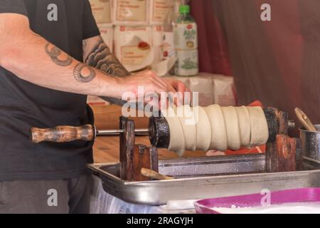 Rohe Kuchenbrötchen aus Schornstein, beliebtes Street Food, zubereitet von einer Tätowierhand Stockfoto