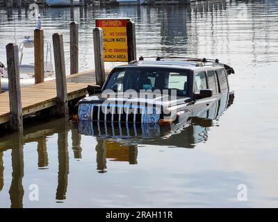 Schwarzes SUV-Fahrzeug, halb von einem hölzernen Dock in einem See eingetaucht Stockfoto