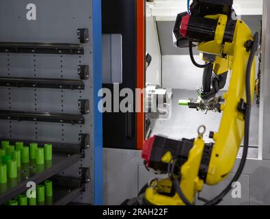 Automatisierter Fertigungsprozess. Roboterarm lädt Werkstücke auf CNC-Drehmaschine. Stockfoto