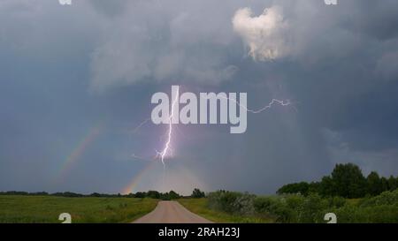 Blitzschlag über dem Regenbogen. Stürmische Landschaft. Stockfoto
