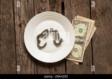 amerikanische Dollar liegen auf einem alten Holztisch neben Handschellen, Finanzen und Korruption Stockfoto
