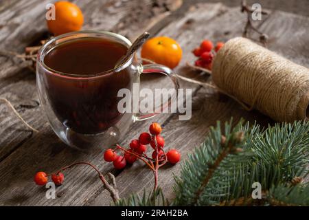 tasse mit Kaffee neben einem Zweig eines weihnachtsbaums Mandarine Zimt auf einem Holztisch, weihnachtstisch mit Kaffee am Morgen Stockfoto