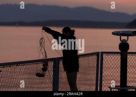 Seattle, USA. 3. Juli 2023. Krabbenfischer und Touristen kommen zusammen, um den Sonnenuntergang in der Elliott Bay zu beobachten, während Seattles Luftqualität deutlich sinkt, während vor den großen Feierlichkeiten am 4. Juli der Rauch des Klimaschutzes in den Puget Sound eindringt. Die PNW wird weiterhin jährlich von klimabezogenem Rauch heimgesucht. James Anderson/Alamy Live News Stockfoto