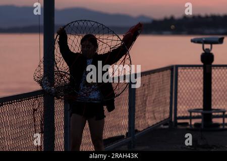Seattle, USA. 3. Juli 2023. Krabbenfischer und Touristen kommen zusammen, um den Sonnenuntergang in der Elliott Bay zu beobachten, während Seattles Luftqualität deutlich sinkt, während vor den großen Feierlichkeiten am 4. Juli der Rauch des Klimaschutzes in den Puget Sound eindringt. Die PNW wird weiterhin jährlich von klimabezogenem Rauch heimgesucht. James Anderson/Alamy Live News Stockfoto