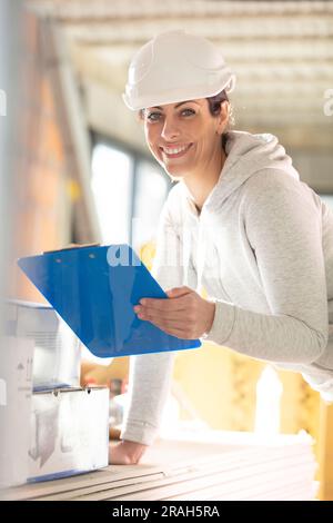 Eine Lagerarbeiterin mit einem lächelnden Papierkram vor der Kamera Stockfoto