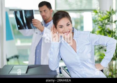 Arzt, der die Röntgenbildgebung hält, während der Patient in die Kamera schaut Stockfoto