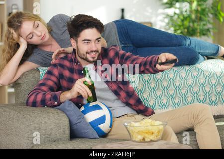 Die Frau langweilte sich, weil ihr Mann Sport im fernsehen guckt Stockfoto