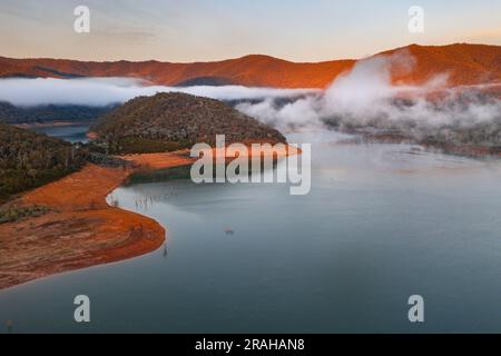 Luftaufnahme des Morgennebels auf der Wasseroberfläche des Eildon-Sees und der umliegenden Berge in Victoria, Australien Stockfoto