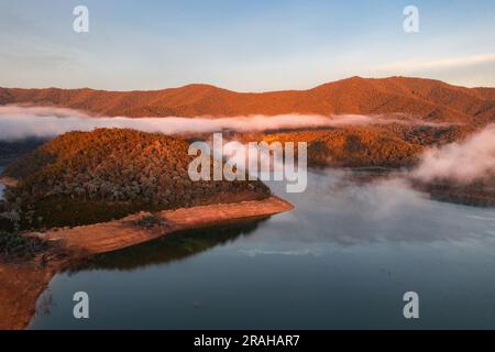 Luftaufnahme des Morgennebels auf der Wasseroberfläche des Eildon-Sees und der umliegenden Berge in Victoria, Australien Stockfoto