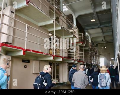 Touristen im Bundesgefängnis Alcatraz blicken auf die Korridore mit Gefängniszellen Alcatraz Island San Francisco California USA Stockfoto